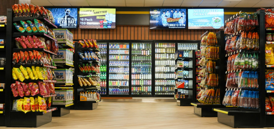 Interior of Shelee's Travel Center convenience store featuring shelves stocked with snacks and a large refrigerator filled with drinks.